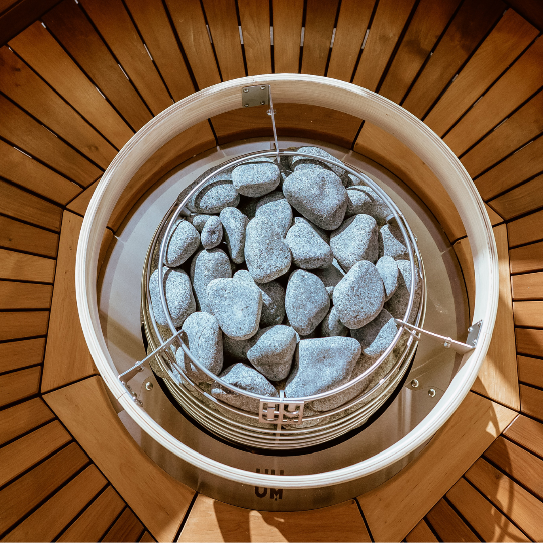 Home sauna recovery with circular bowl of rocks on wooden floor.