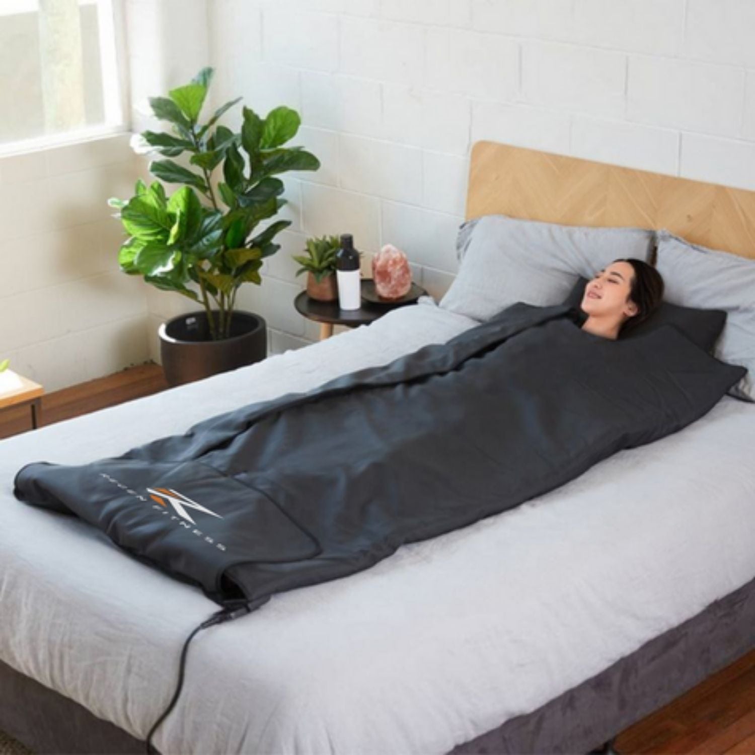 A woman on a bed enjoying a home sauna with the RegenHeat infrared sauna blanket.