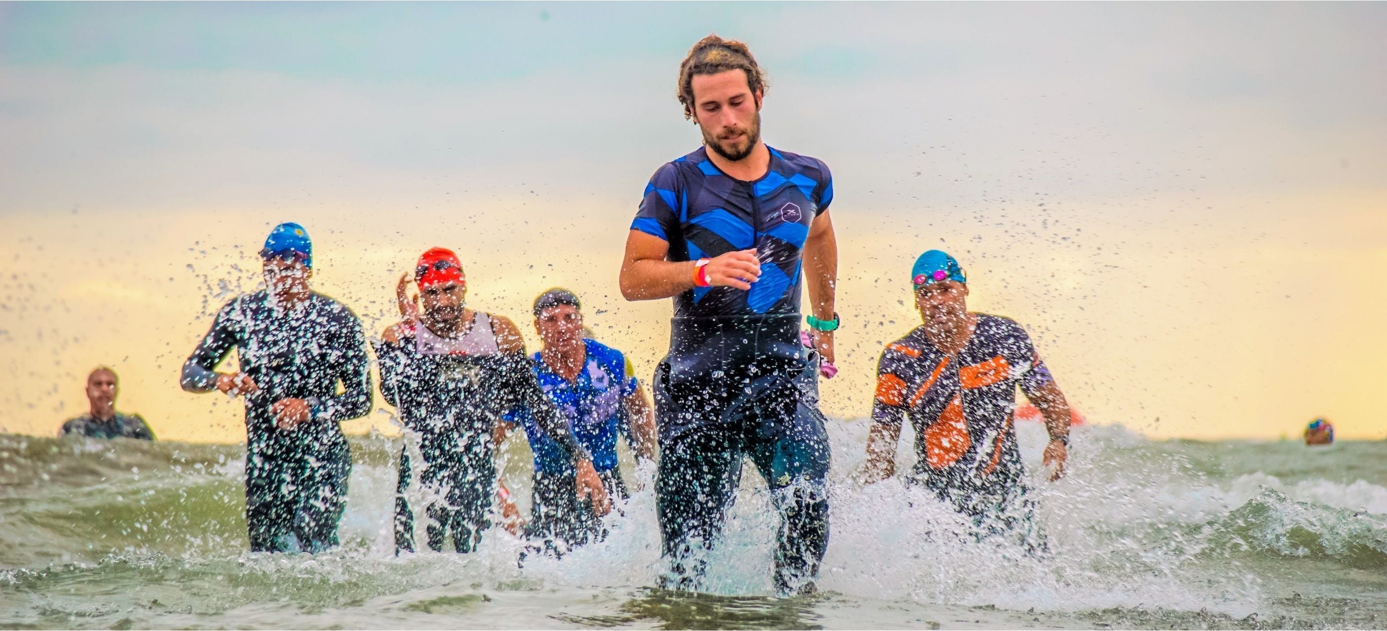 Athletes engaged in a triathlon, energetically running in the ocean as part of the challenging race.