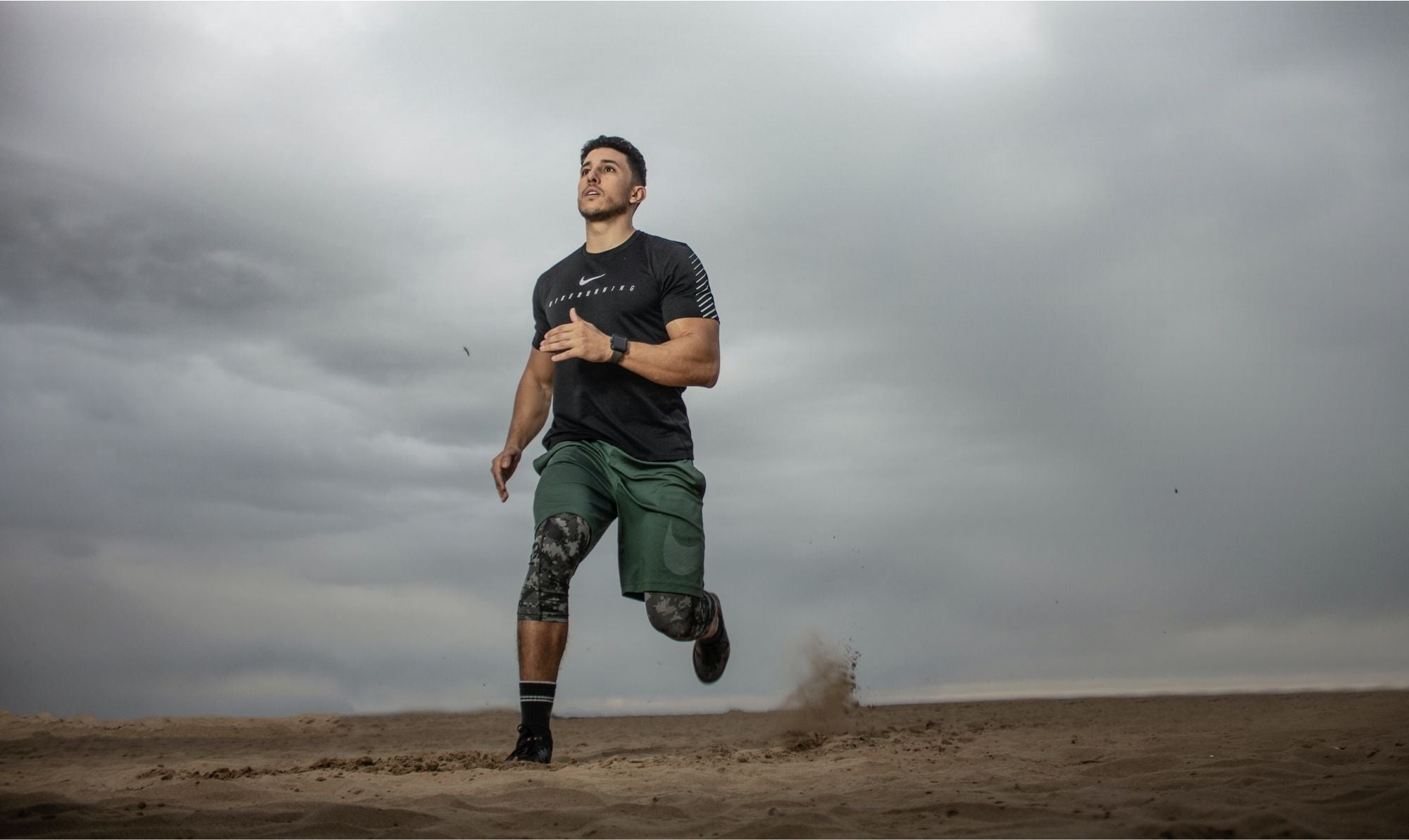 Endurance runner on sandy beach with cloudy sky