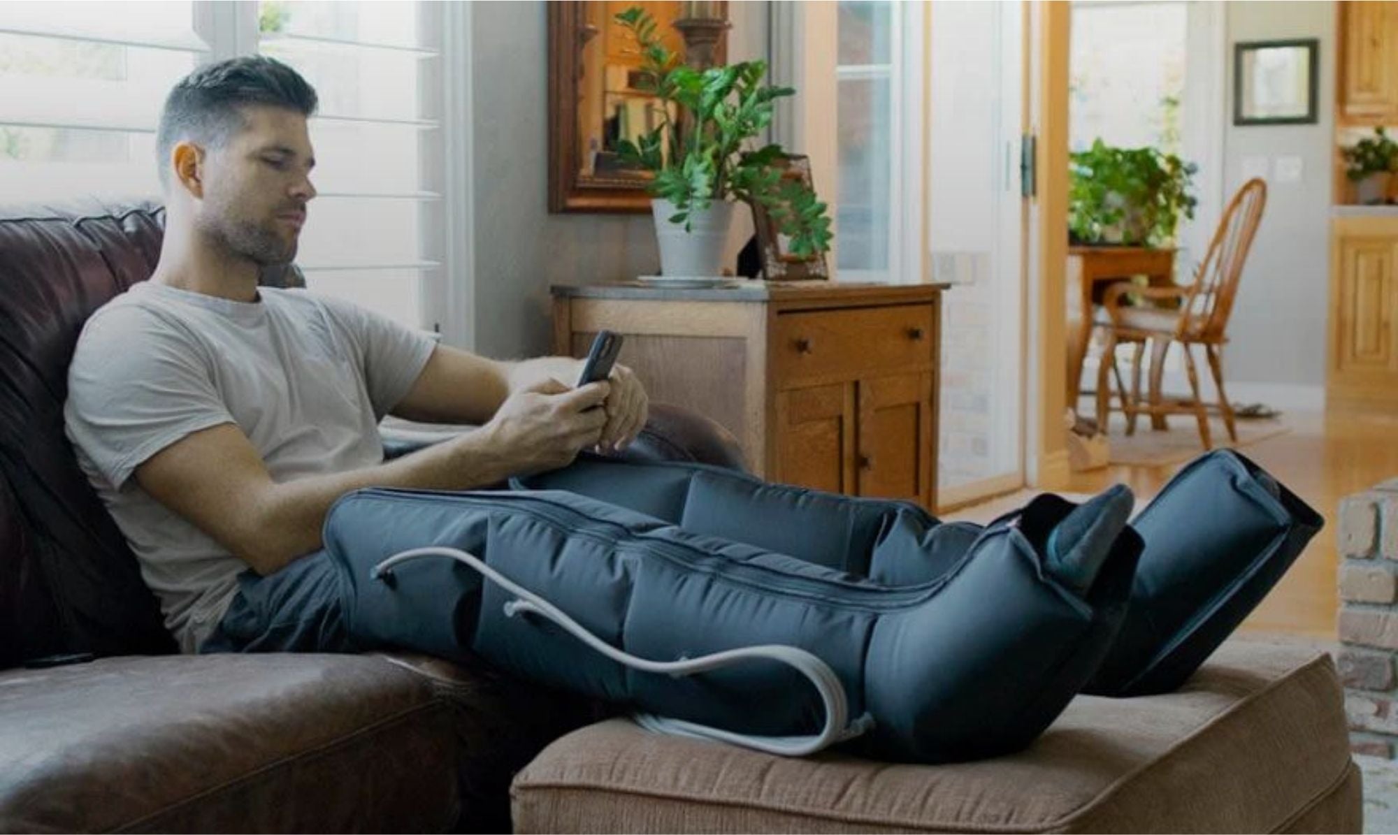 Man on sofa recovering after a workout, receiving compression therapy using RegenAir 